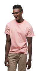Fototapeta premium Young african american man wearing pink t-shirt winking looking at the camera with sexy expression, cheerful and happy face.