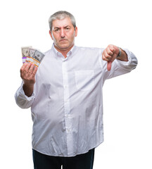 Handsome senior man holding bunch of money over isolated background with angry face, negative sign showing dislike with thumbs down, rejection concept