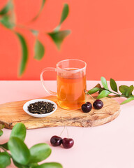Glass tea cup of cherry herbal tea on pink and red background