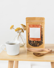 Cup of tea with blank tea packaging on styled table