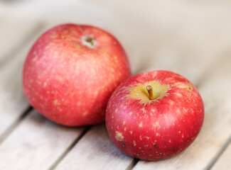Two red apples on a wooden table indoors. Eat healthy and watch your diet. Fruit contains essential vitamins to boost your immunity. Closeup of a delicious snack vegans and vegetarians can enjoy