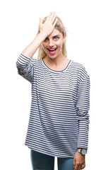 Young beautiful blonde woman wearing stripes sweater over isolated background surprised with hand on head for mistake, remember error. Forgot, bad memory concept.