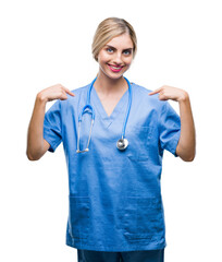 Young beautiful blonde doctor surgeon nurse woman over isolated background looking confident with smile on face, pointing oneself with fingers proud and happy.