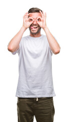 Young handsome man over isolated background doing ok gesture like binoculars sticking tongue out, eyes looking through fingers. Crazy expression.