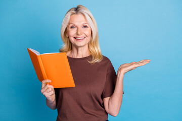 Photo of adorable clever smart woman wear trendy brown clothes hold book empty space isolated on blue color background