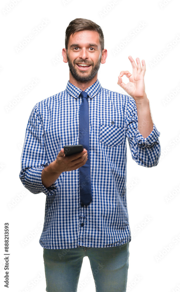 Sticker Young hadsome man texting sending message using smartphone over isolated background doing ok sign with fingers, excellent symbol