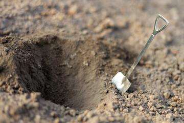 A shovel is stuck in the ground in a dirt hole
