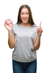 Obraz premium Young caucasian woman eating sweet donut over isolated background surprised with an idea or question pointing finger with happy face, number one
