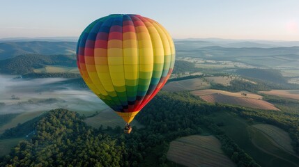 Fototapeta premium A vividly colored hot air balloon soaring over an expansive green landscape with rolling hills, offering a stunning aerial view and encapsulating freedom and adventure from above.