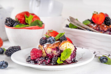 Homemade sweet berry cobbler pie cake with various garden forest berries - strawberry, blackberry, blueberry, healthy summer dessert recipe in baking pan and plate, copy space