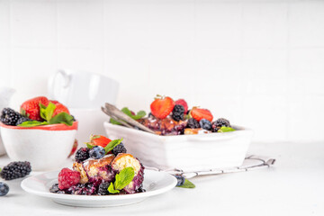 Homemade sweet berry cobbler pie cake with various garden forest berries - strawberry, blackberry, blueberry, healthy summer dessert recipe in baking pan and plate, copy space