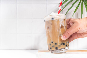 Classic boba bubble tea with tapioca pearls and whipped non-dairy creamer on top of glass, summer...
