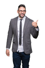 Young handsome business man over isolated background smiling with happy face looking and pointing to the side with thumb up.