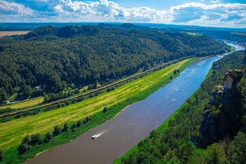 a narrow river flows in the mountains, many green trees, blue sky, clouds © Anastasiia