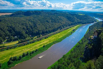 Fototapeten Wald Fluss a narrow river flows in the mountains, many green trees, blue sky, clouds  © Anastasiia