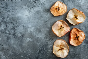 Four dehydrated apple slices on a bare concrete surface