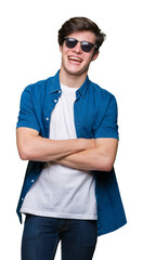 Fototapeta premium Young handsome man wearing sunglasses over isolated background happy face smiling with crossed arms looking at the camera. Positive person.