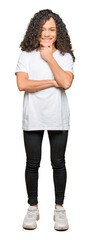 Obraz premium Young beautiful woman with curly hair wearing white t-shirt looking confident at the camera with smile with crossed arms and hand raised on chin. Thinking positive.