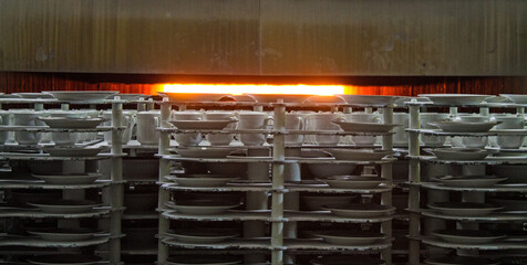 New ceramic identical white dishes sent to a muffle kiln for firing at a porcelain factory in the...