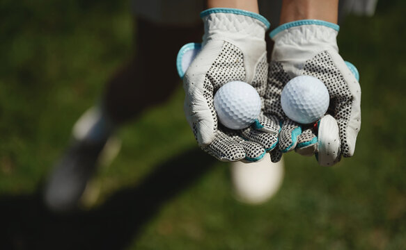 Closeup of golf gloves with two golf balls on green field