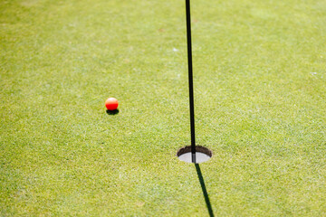 Golf ball near hole on a sunny day