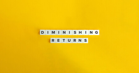 Diminishing Returns Term and Text on Block Letter Tiles against Yellow Background. 