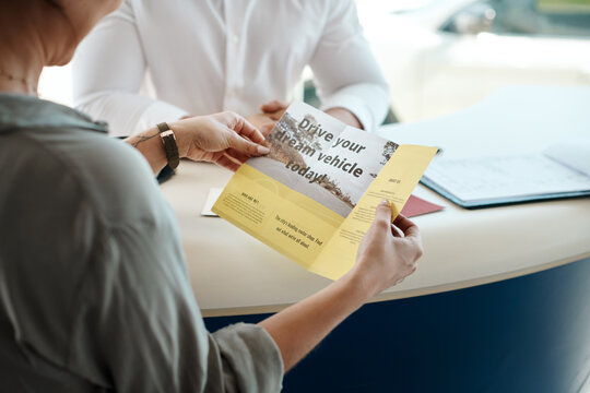 Car dealership, woman and hands with flyer for motor purchase and brochure for shopping. Showroom, deal and retail sale document at customer consultation meeting with reading an advertisement