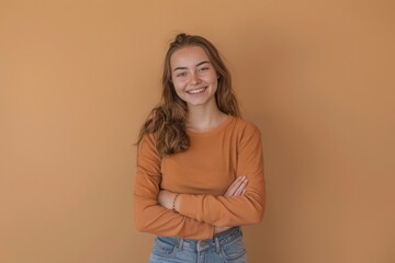 Obraz premium cheerful young woman standing with her arms crossed and smiling at the camera