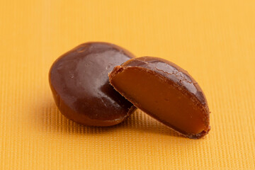 Sweet Chocolate Covered Caramel Disks on Yellow Background