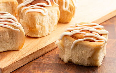 Drizzled Homemade Bready Cinnamon Roll Buns on a Wood Board