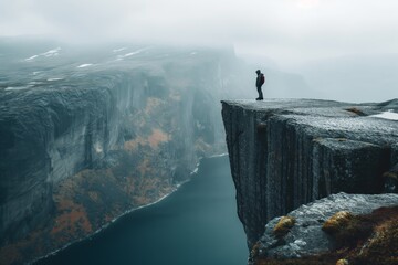 A man stands on a cliff overlooking a body of water. The scene is serene and peaceful, with the man's backpack adding a sense of adventure to the image
