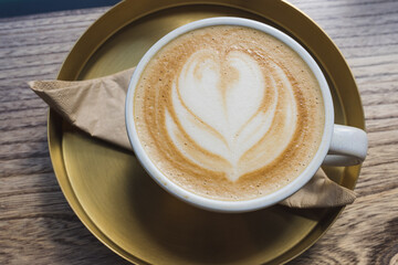 Cappuccino with Heart Latte Art on Wooden Table in Golden Saucer at Cafe