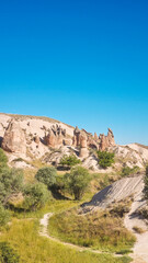 Fototapeta premium Landscape with path through imagination valley national geology park with fantastic volcanic tuff formations, green grass and bushes and clear blue sky is a travel destination for hiking or trekking