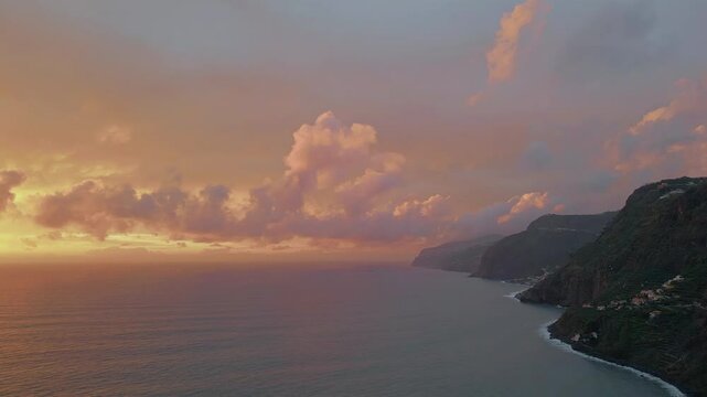 Serene sundawn coastal cliffs washed by ocean waves aerial view. Golden sunrise