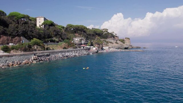 Aerial view ascending above the rocky shore of Celle Ligure in the Italian region Liguria with blue sea and canoe