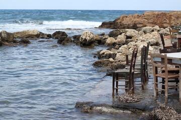 Fototapeta premium chair from a restaurant on the beach in hanja, no people, waves in a cafe in the evening on the beach in the city of Chania