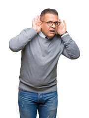 Middle age bussines arab man wearing glasses over isolated background Trying to hear both hands on ear gesture, curious for gossip. Hearing problem, deaf