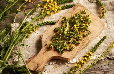 Chopped fresh agrimony flowers on a wooden cutting board - ingredient for herbal tincture