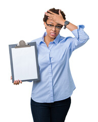 Young african american businesss woman holding clipboard over isolated background stressed with hand on head, shocked with shame and surprise face, angry and frustrated. Fear and upset for mistake.