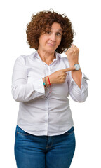 Beautiful middle ager senior businees woman over isolated background In hurry pointing to watch...