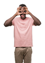 Young african american man wearing pink t-shirt doing ok gesture like binoculars sticking tongue out, eyes looking through fingers. Crazy expression.