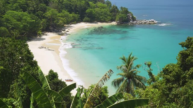 Serene aerial view of secluded cove with turquoise waters, lush greenery, and pristine sands in Singh Beach, Phuket, Thailand