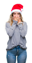 Beautiful young blonde woman wearing christmas hat over isolated background shocked covering mouth with hands for mistake. Secret concept.