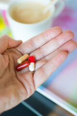 Close up of caucasian female hand with pills at breakfast