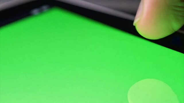 Macro close up of a finger using a touchscreen on an electronic voting machine during an election. Touch screen is a chroma green screen.