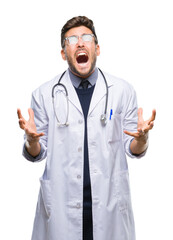 Fototapeta premium Young handsome doctor man over isolated background crazy and mad shouting and yelling with aggressive expression and arms raised. Frustration concept.