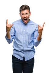 Fototapeta premium Young handsome man over isolated background shouting with crazy expression doing rock symbol with hands up. Music star. Heavy concept.