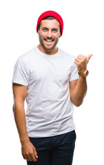 Naklejka premium Young handsome man over isolated background smiling with happy face looking and pointing to the side with thumb up.