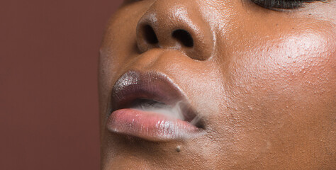 dark skin woman exhaling smoke between her lips, Brown skinned woman smoking a cigarette
