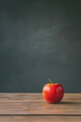 Single red apple on a wooden table with a dark background, representing health, simplicity, and education